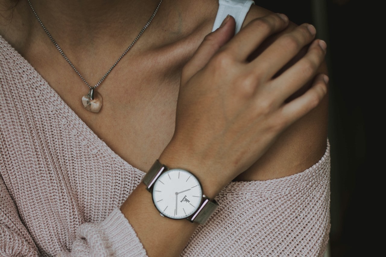 woman holding shoulder with watch