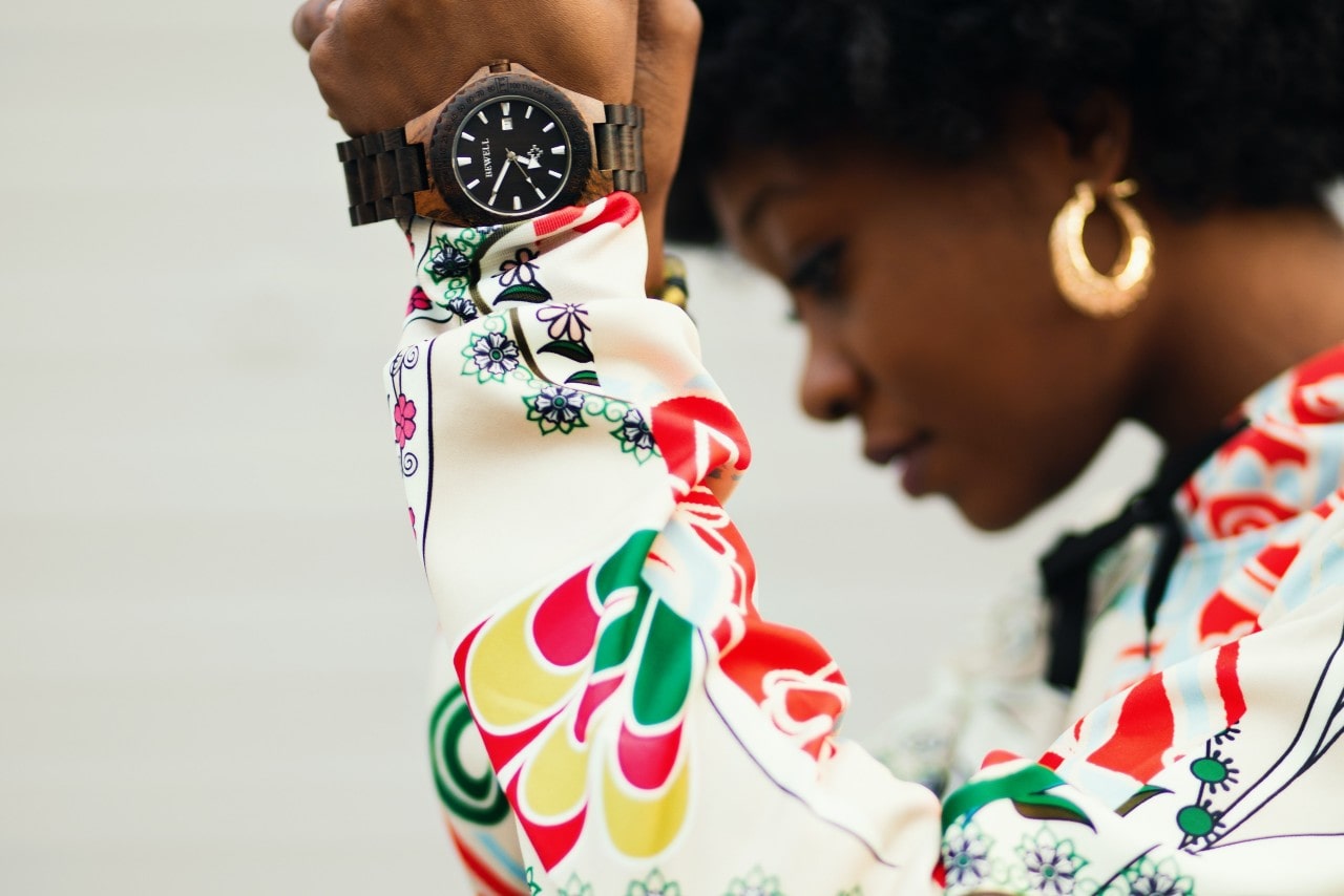 A woman in a colorful shirt holding up a luxurious watch