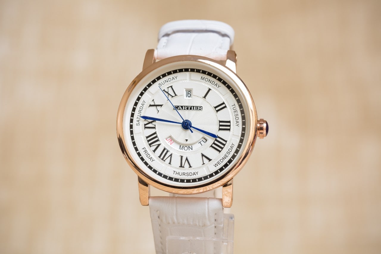 Cartier watch with a rose gold bezel, white dial, and Roman numeral indices
