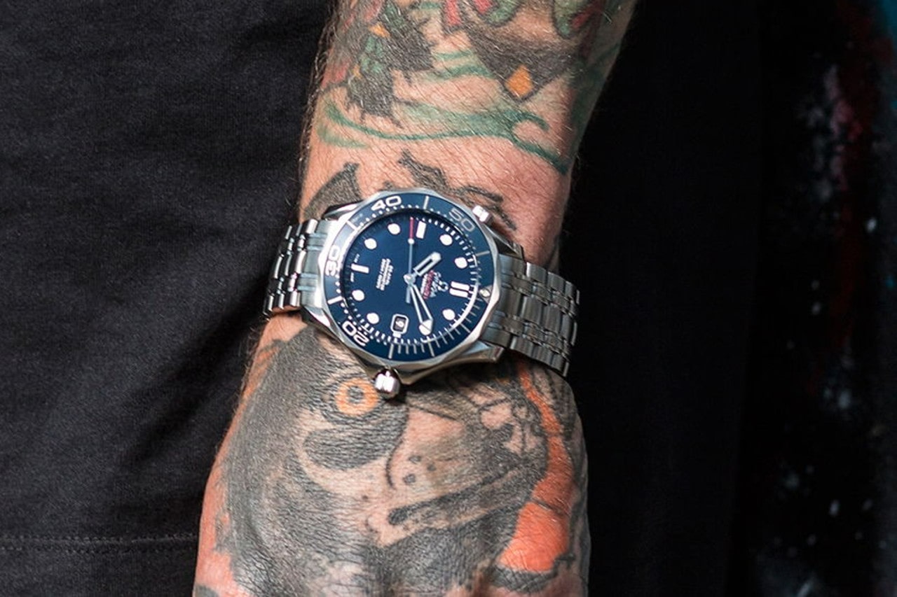 A tattooed man sports a classic Omega watch on a casual outing in the city
