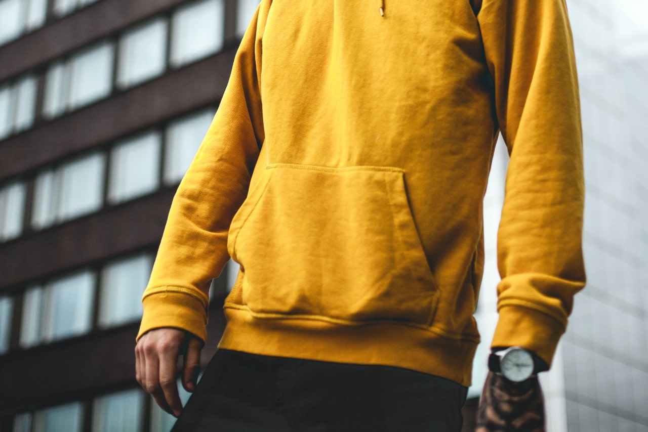Casually dressed person wearing a yellow hoodie and a marvelous watch