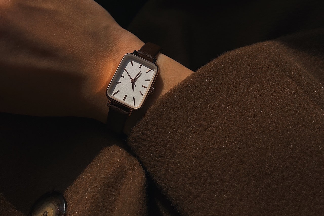 Close-up of a person’s arm wearing a brown coat and a rectangular watch