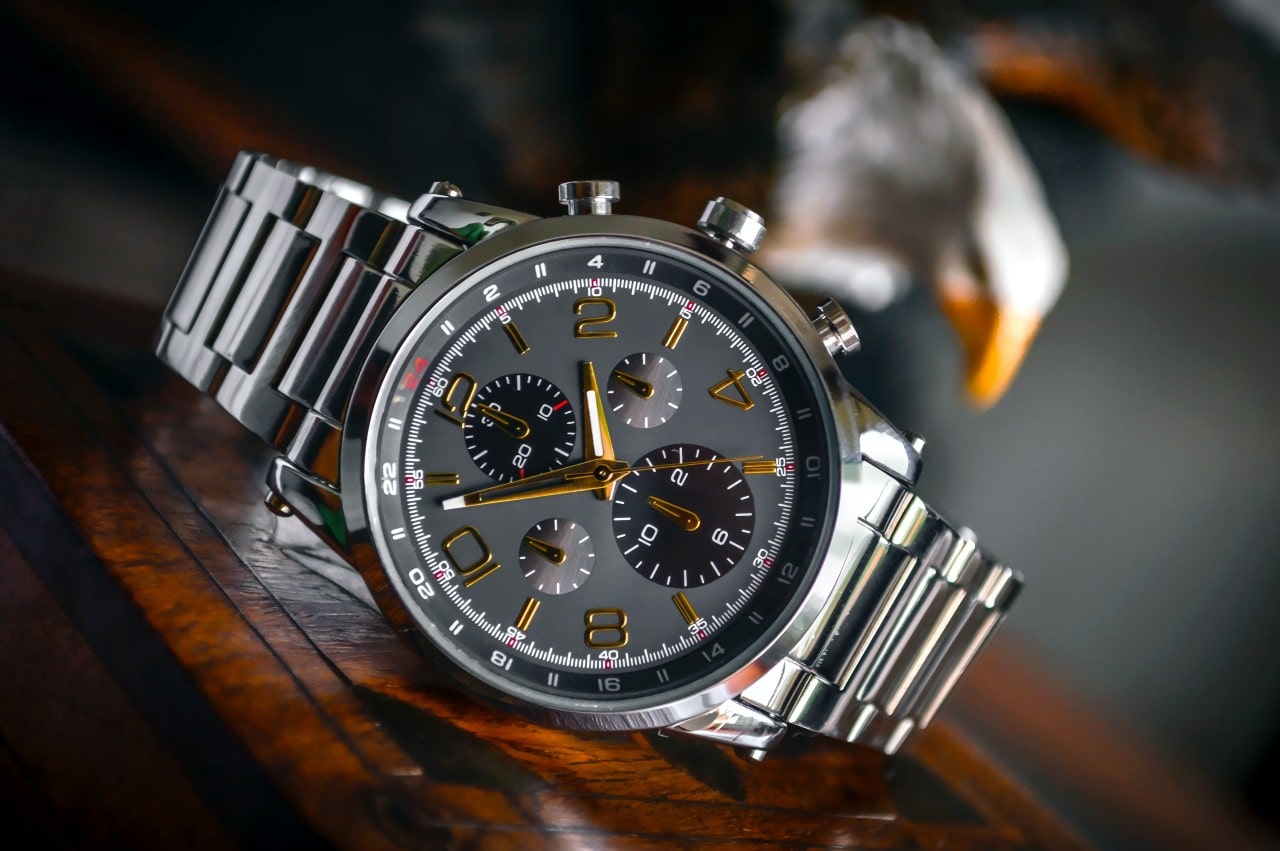 Stainless steel watch with chronograph sitting on a wooden table