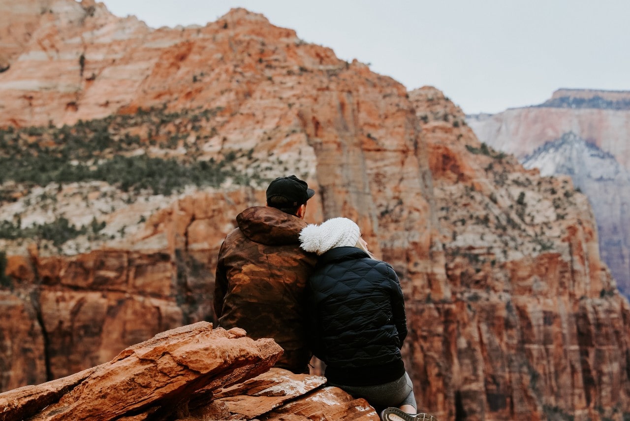 A couple sits down and rests while exploring a canyon
