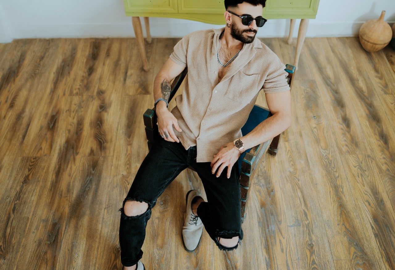 Man sitting in a chair wearing a watch and fashionable clothes