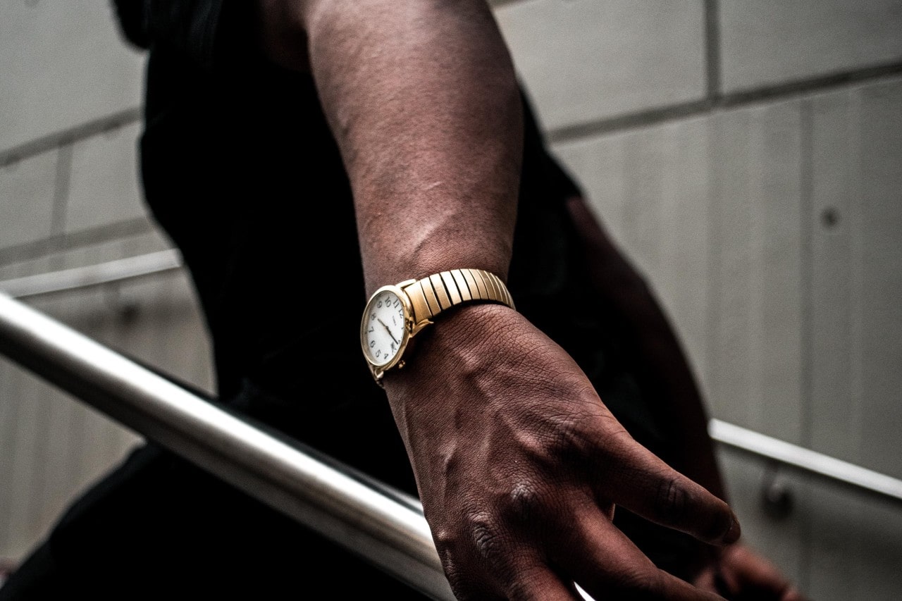 close-up image of a man walking upstairs and wearing a gold watch