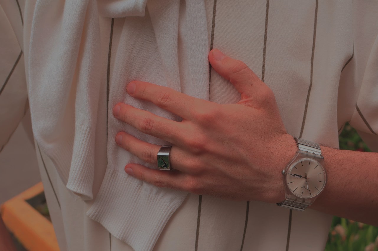 a platinum watch and male’s signet ring resting on a man’s chest