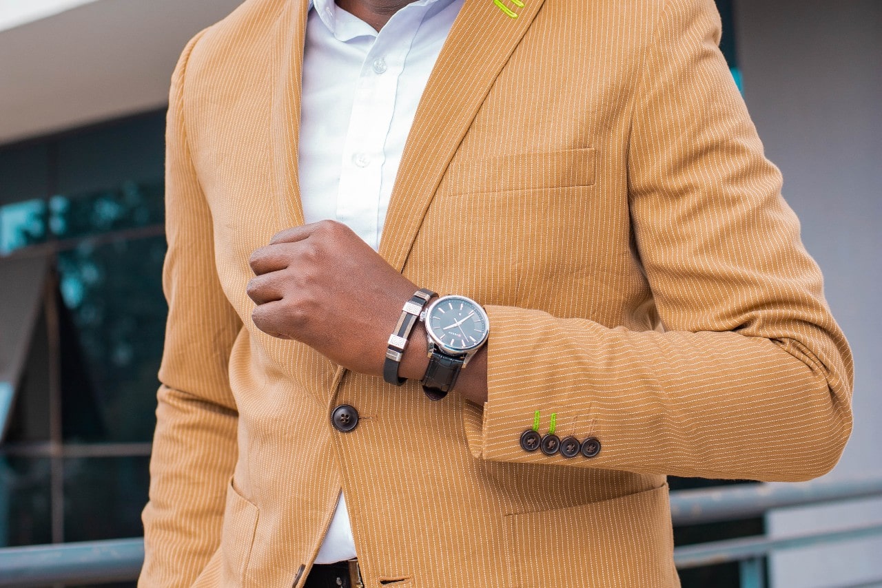 A man in an orange suit sports a casual timepiece with a bracelet.