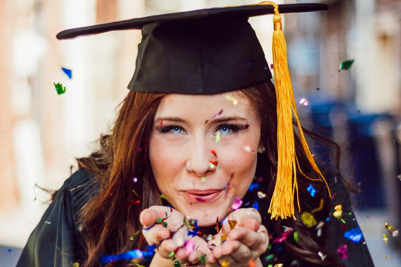 woman graduation and blowing confetti