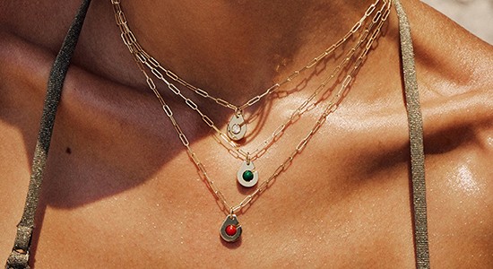 close up image of a woman’s neck adorned with three gemstone necklaces by Dinh Van