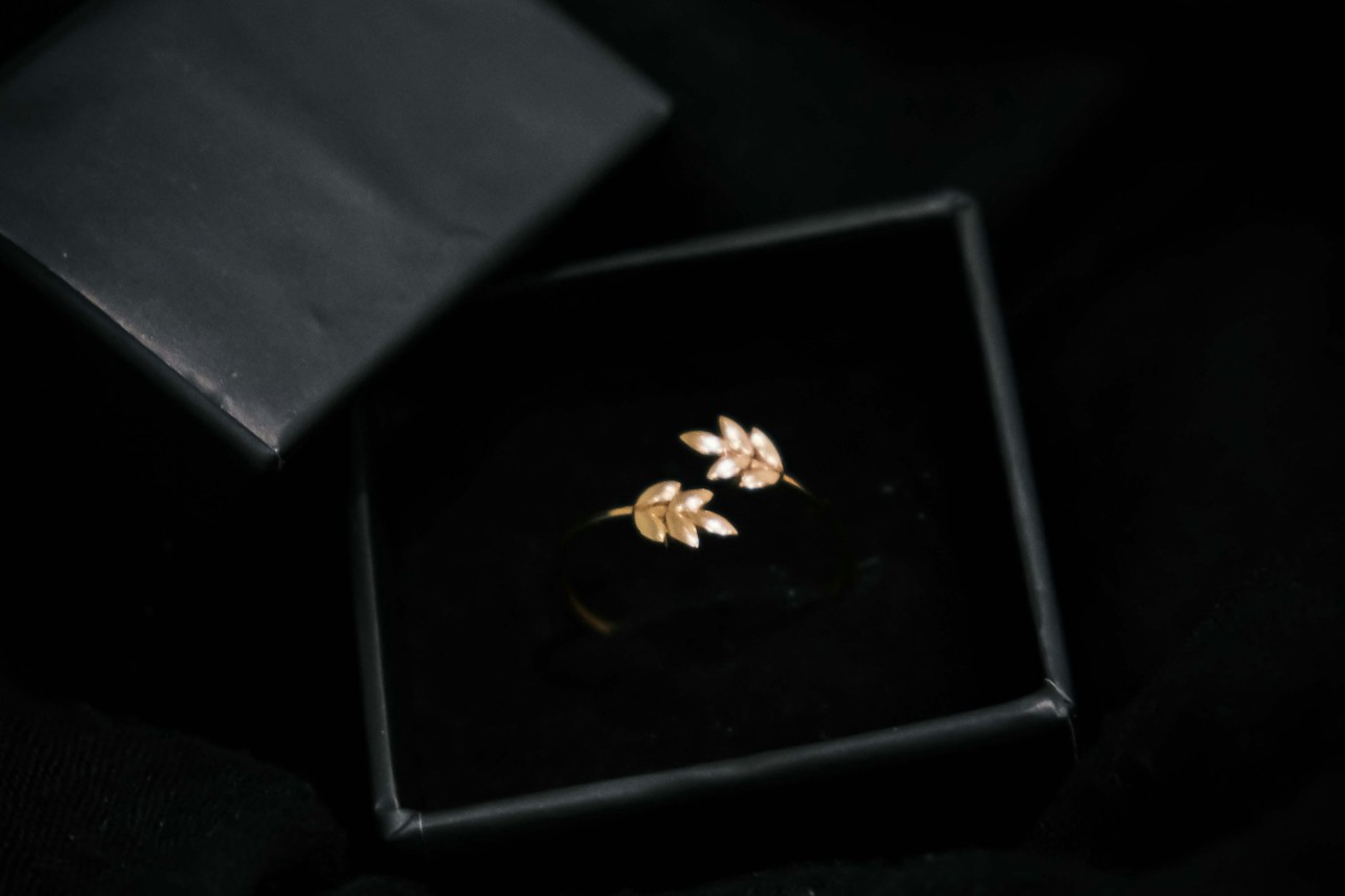 a yellow gold ring with leaf motifs in a black box