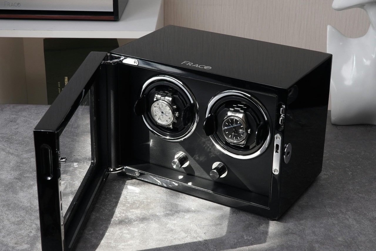 two silver watches in a black watch winder case