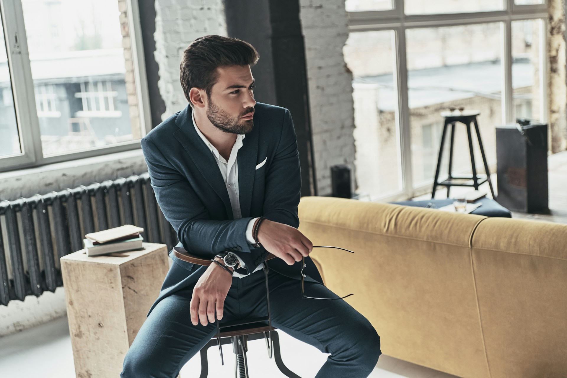 A well-dressed young man in a chic apartment, wearing a luxury watch.