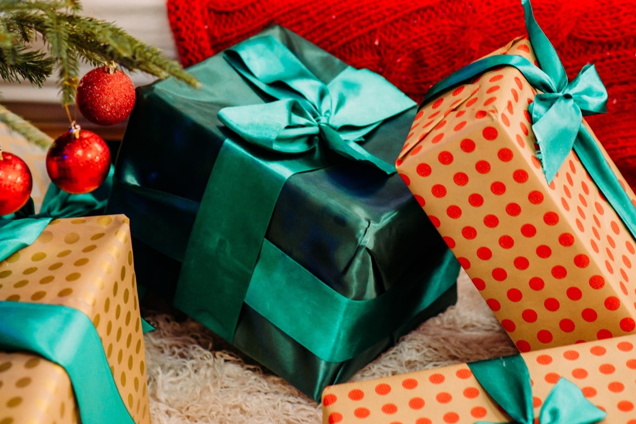 A close-up of an elegant green gift among polka-dotted Christmas packages under the tree.