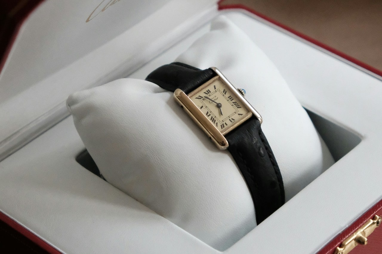 A close-up of a Cartier tank watch, displayed in-box.