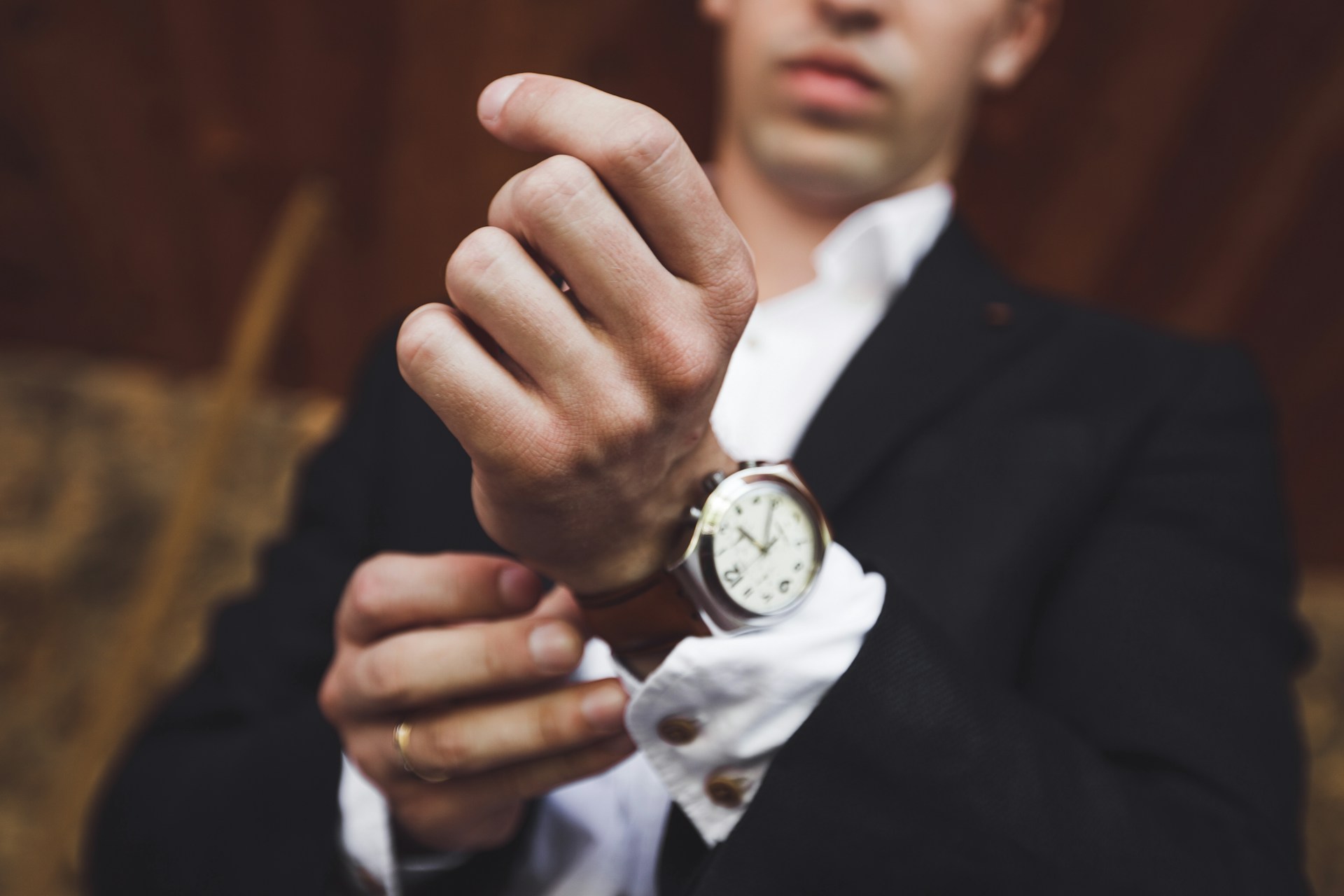 A close-up of a man wearing a fine suit and a luxury watch.