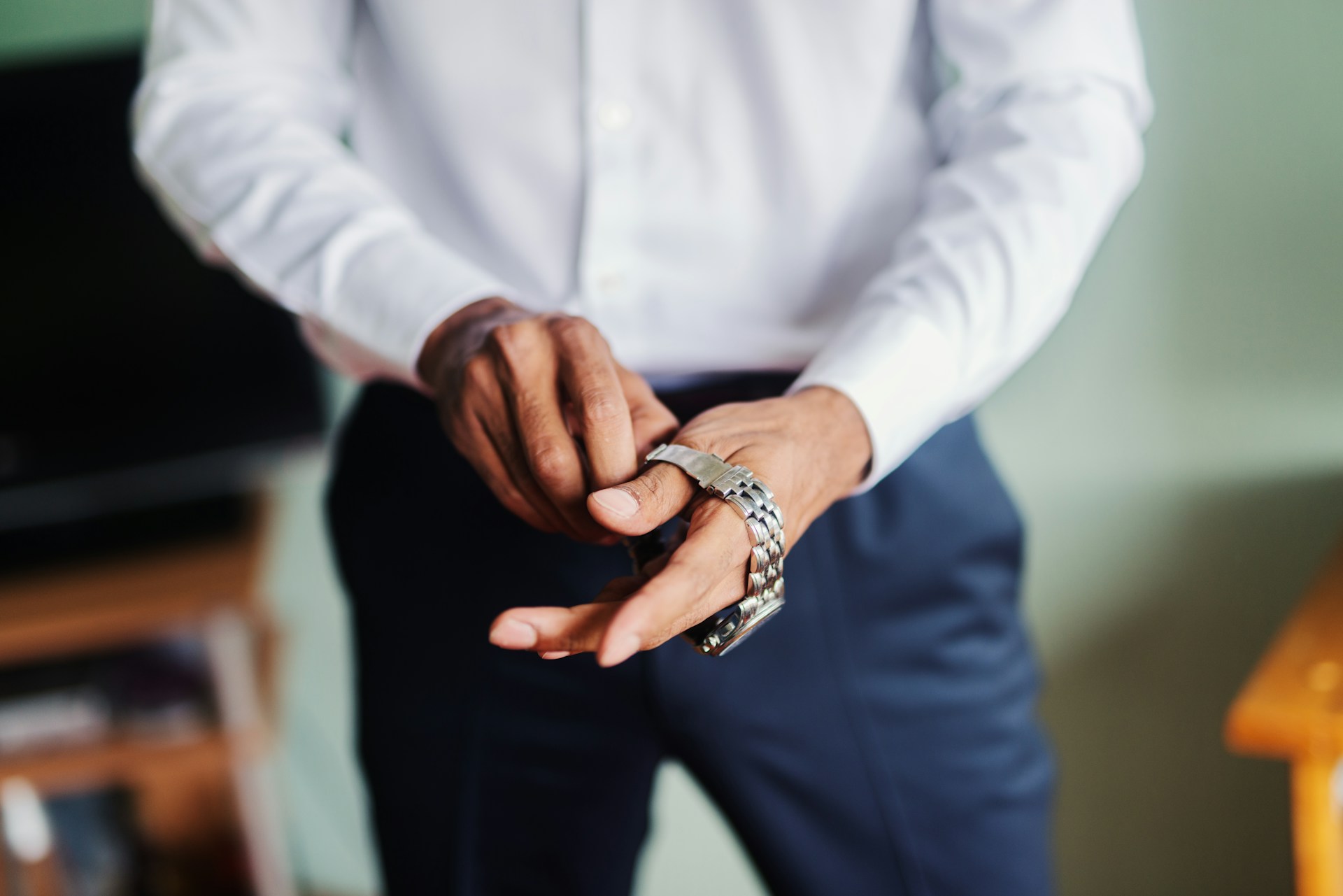 A close-up of a man’s hands as he puts on a luxury watch.