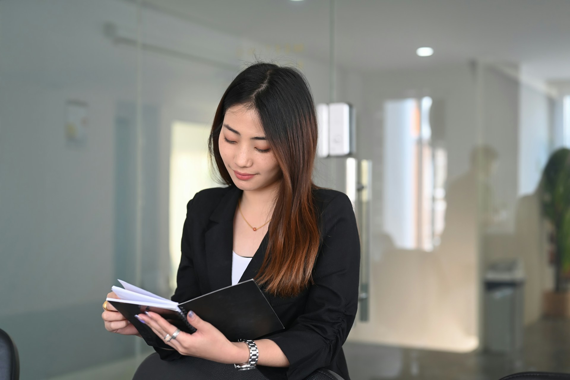 A well-dressed woman wearing a luxury watch while reading the book.