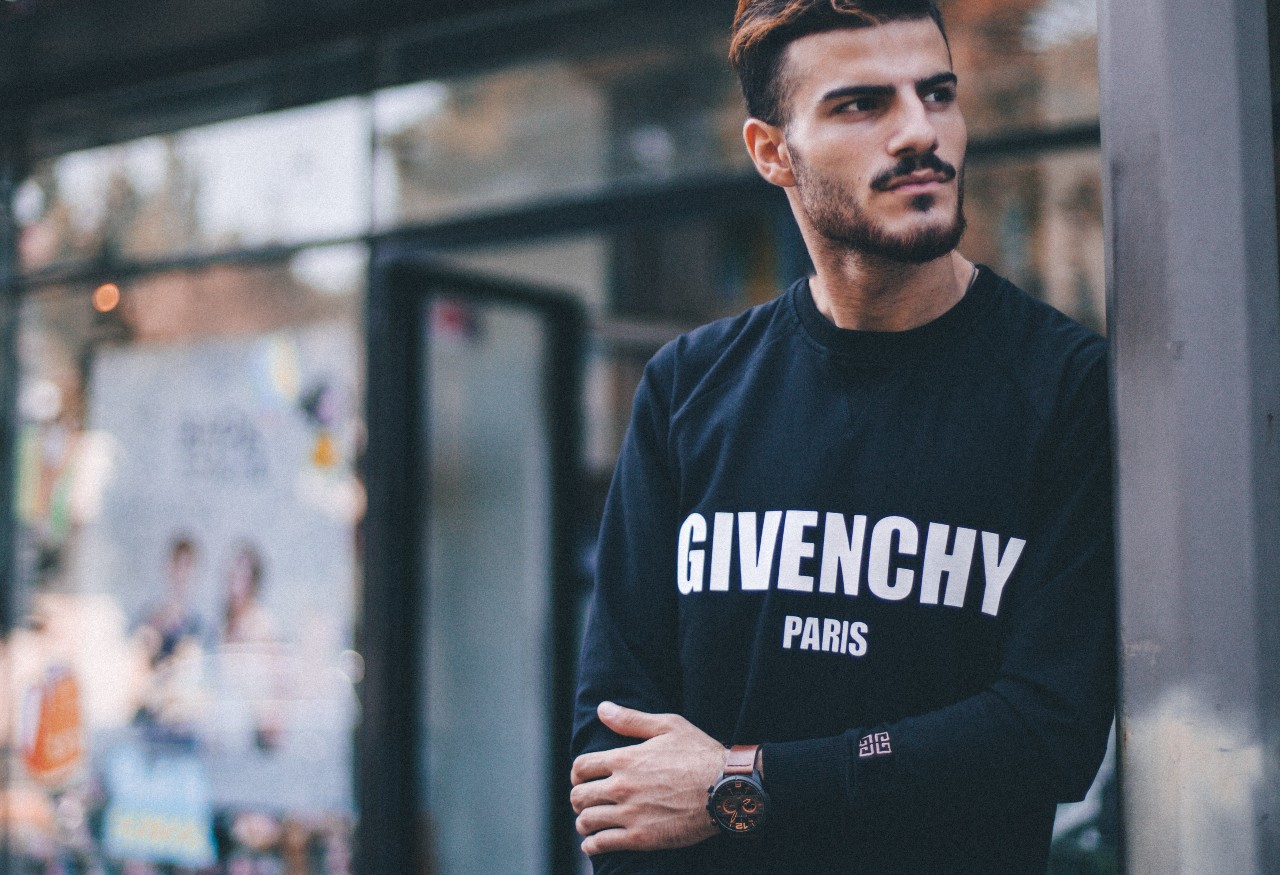 a man in a Givenchy sweatshirt and a black and brown watch.