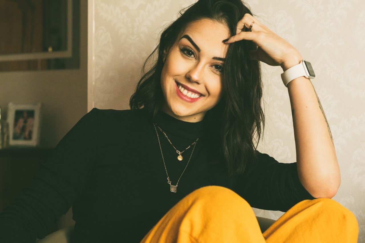 smiling lady wearing necklaces, a watch, and stylish clothes