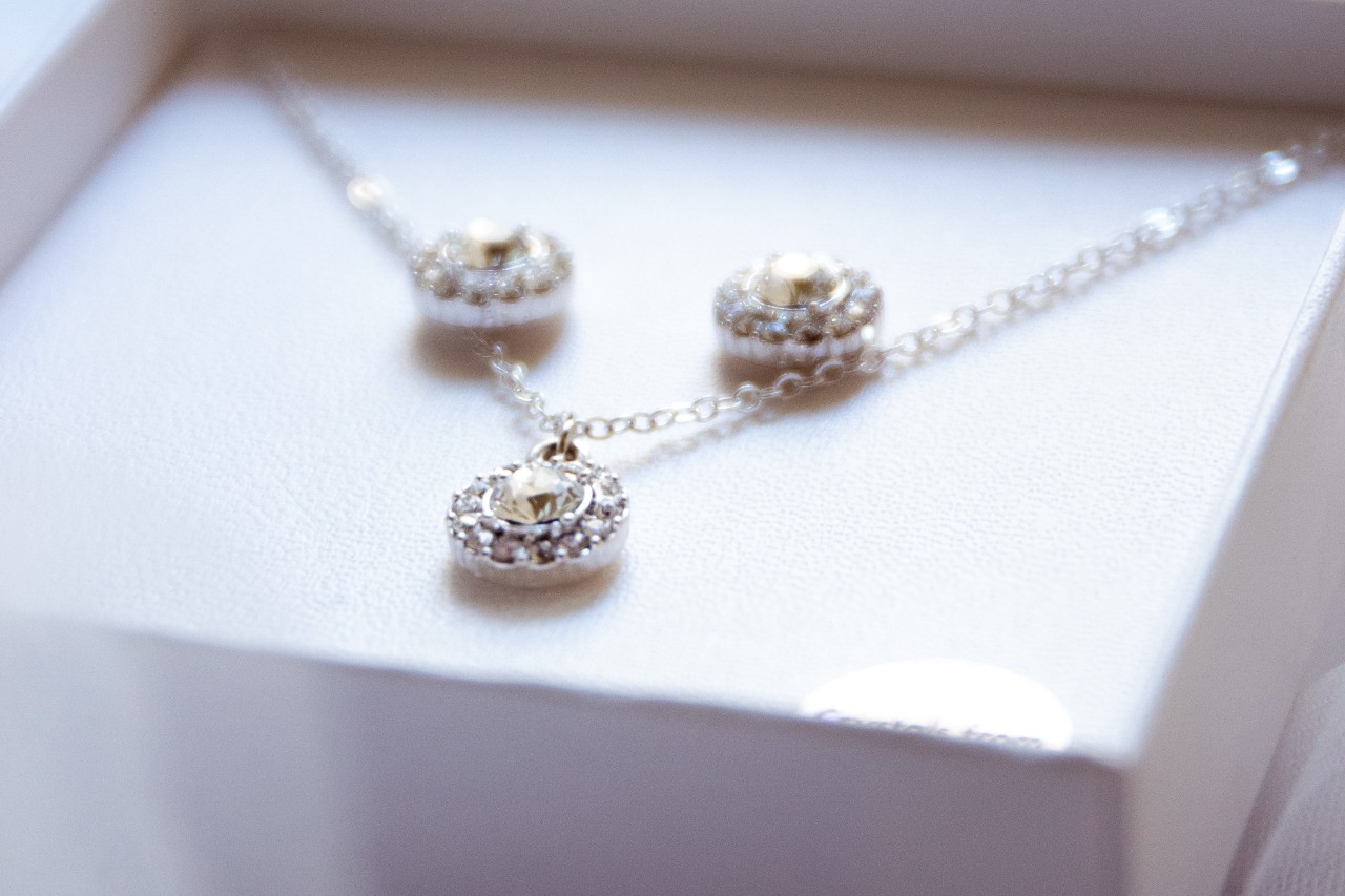 A close-up of a matching set of diamond earrings and a necklace displayed in-box.