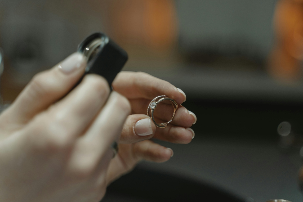 A close-up of a jeweler inspecting a diamond ring with a loupe.