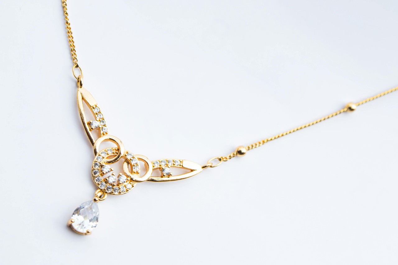 close up image of a yellow gold diamond pendant necklace with an intricate design