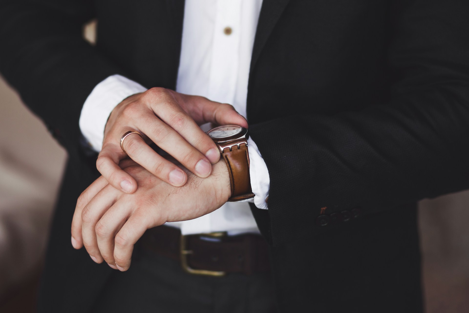 a man’s hands checking his watch