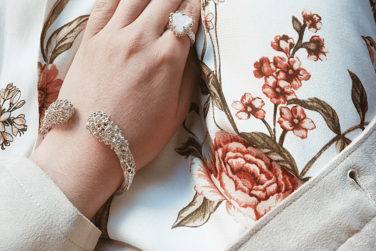 A woman wearing a cuff bracelet rests her hand on her chest. A woman wearing a cuff bracelet rests her hand on her chest.